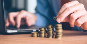 man stacking coins next to laptop