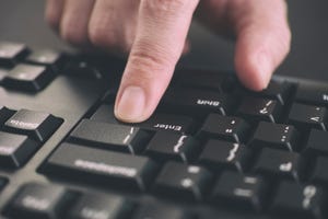 Person typing on a keyboard and pressing Enter key