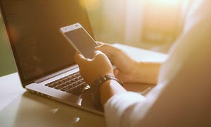 person working from home using smart phone and notebook computer